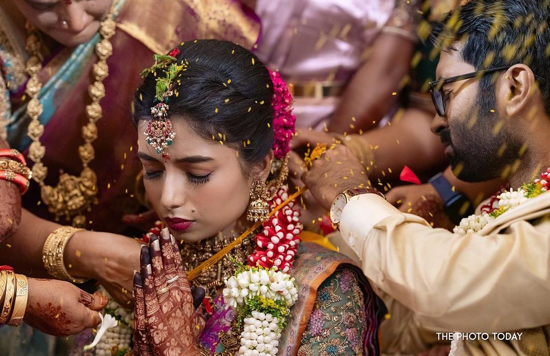 A South Indian bride is being beautified by her groom during a bridal photoshoot.