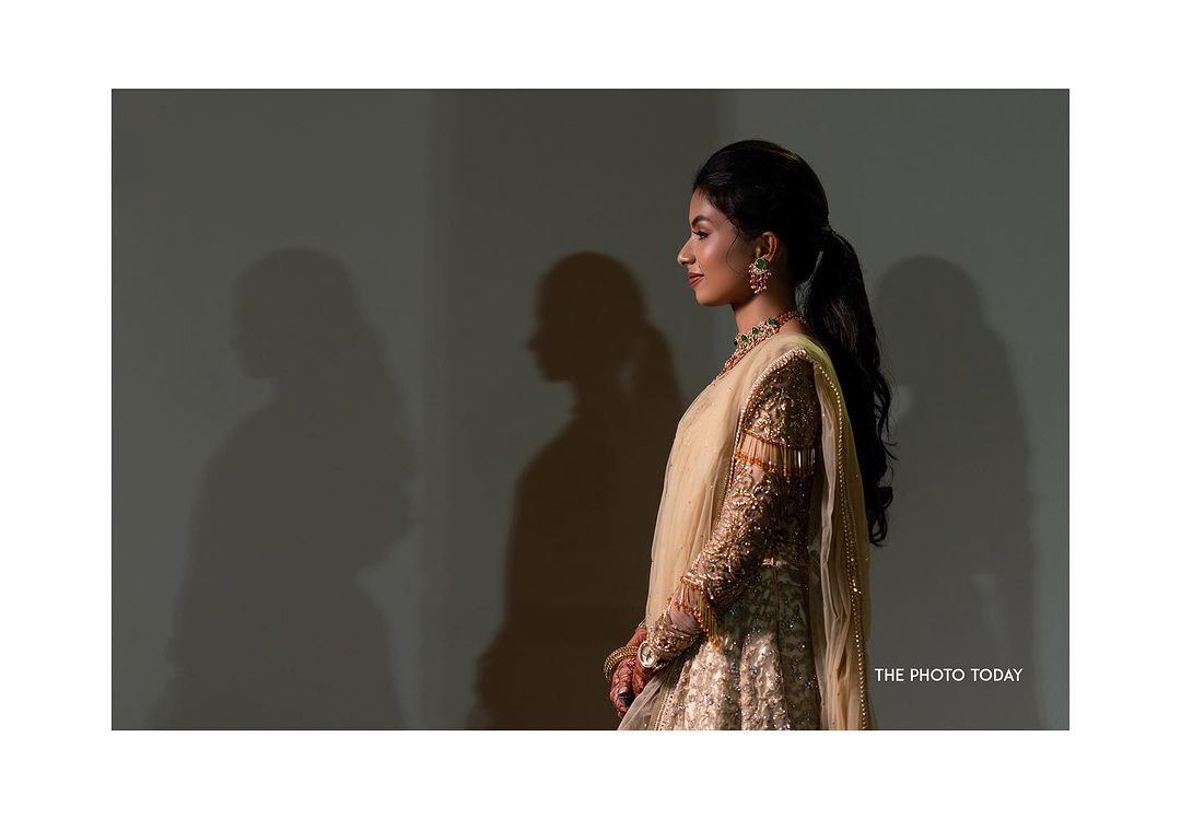 A South Indian bride in traditional attire admiring herself in a mirror during a bridal photoshoot.